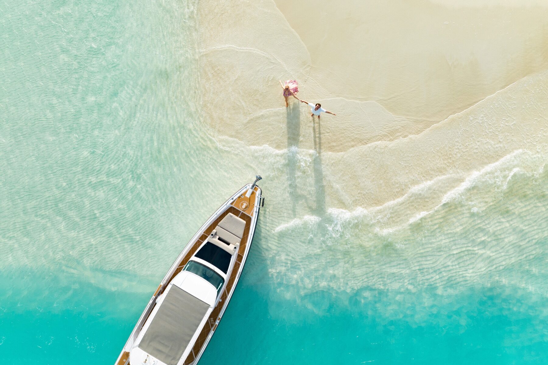 Aerial view of a couple walking toward a boat on a Turks and Caicos sandbar