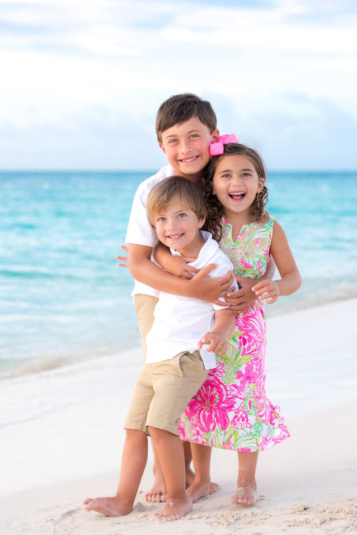 Three siblings hugging and smiling together on a Turks and Caicos beach