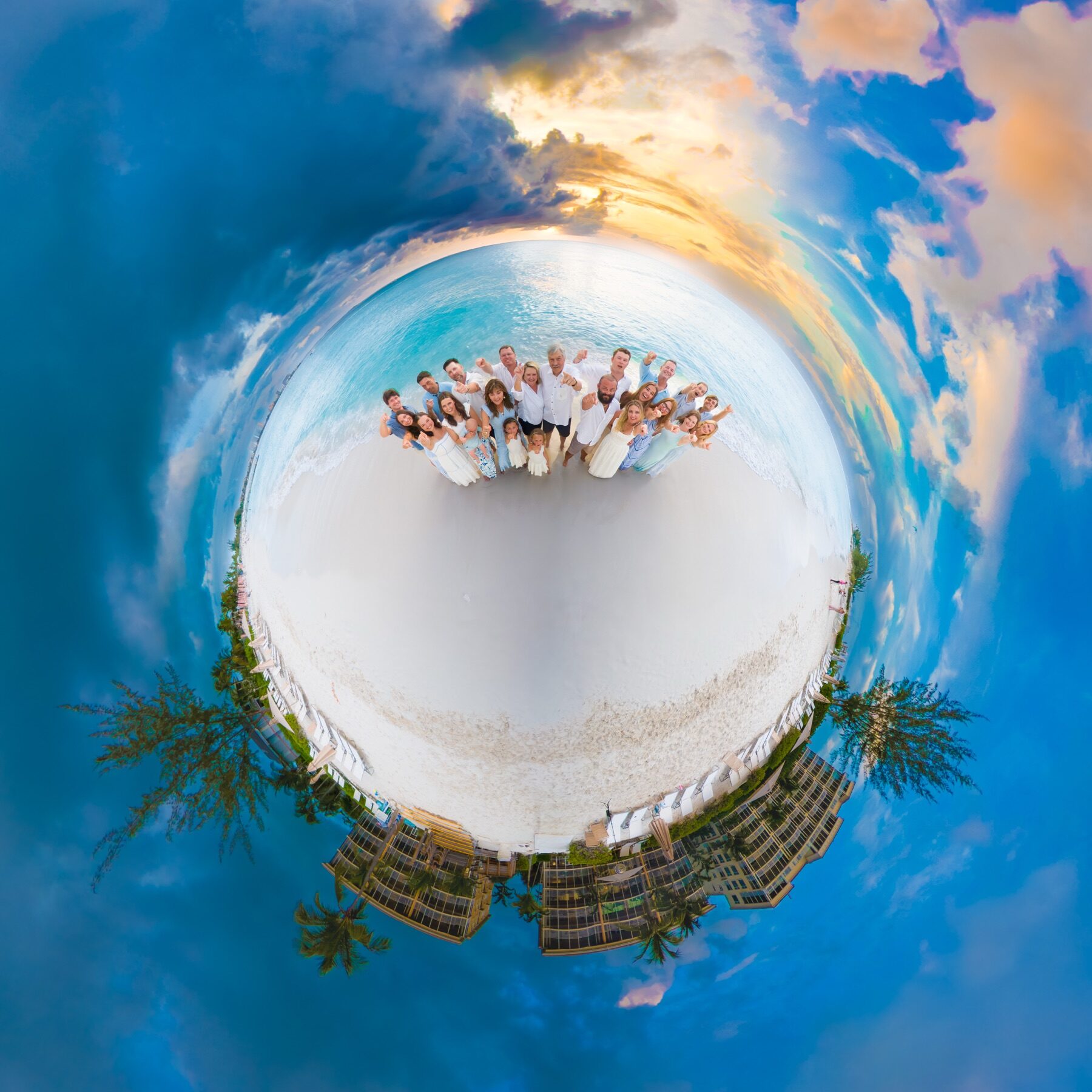 Little planet panorama of a large family group posing on a curved beach