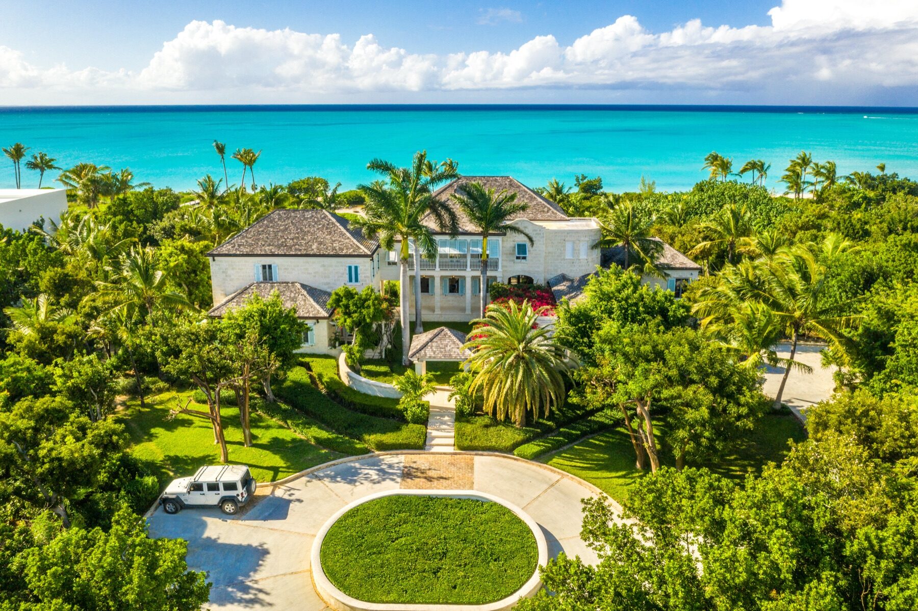 Aerial view of a stone villa surrounded by palm trees near the ocean