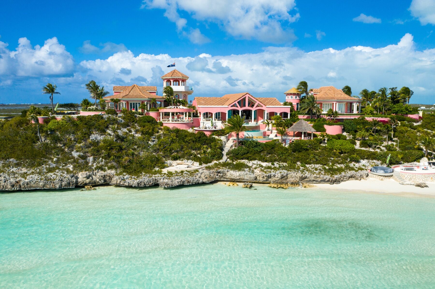 Aerial view of a pink villa estate perched on a rocky Turks and Caicos point