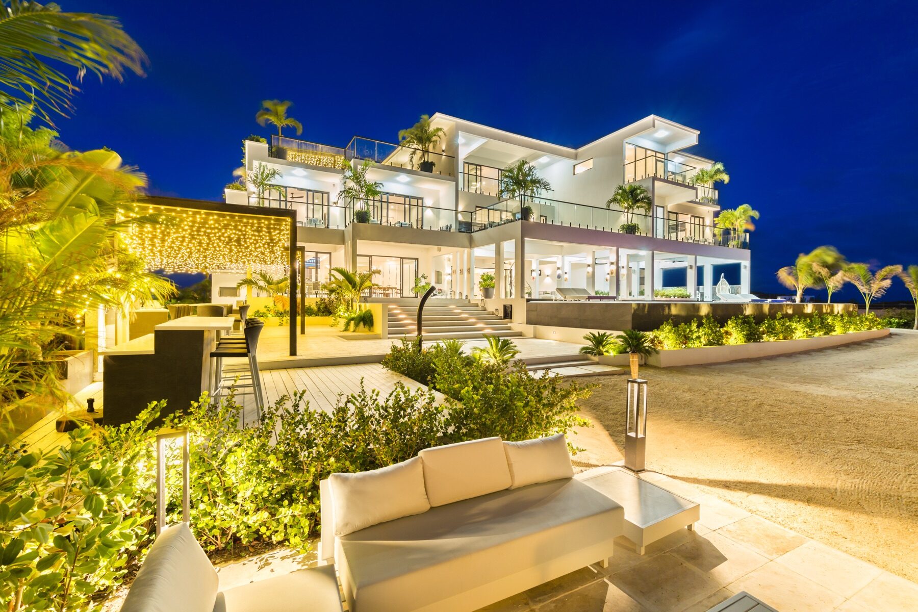 Multi story villa exterior glowing with lights against a night sky