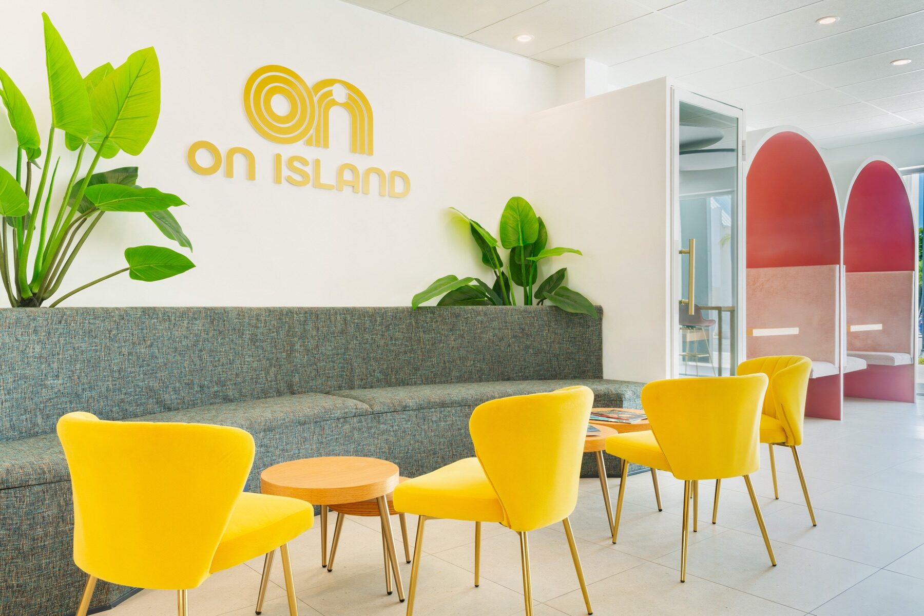 Bright lobby lounge with yellow chairs beneath an On Island sign