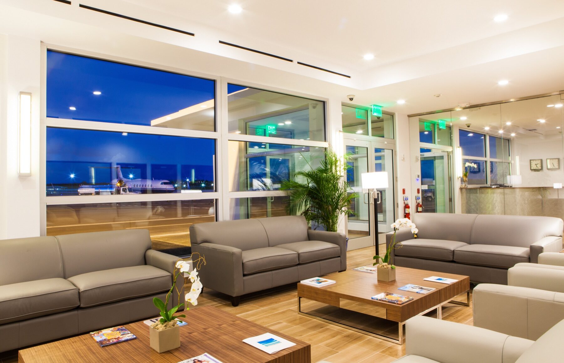 Airport style lounge with leather sofas facing a lit runway at night