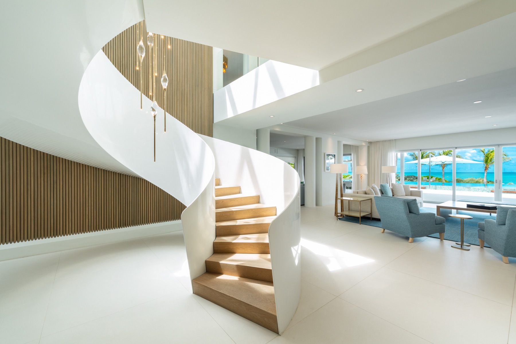 Curved white staircase leading up from a bright open living area