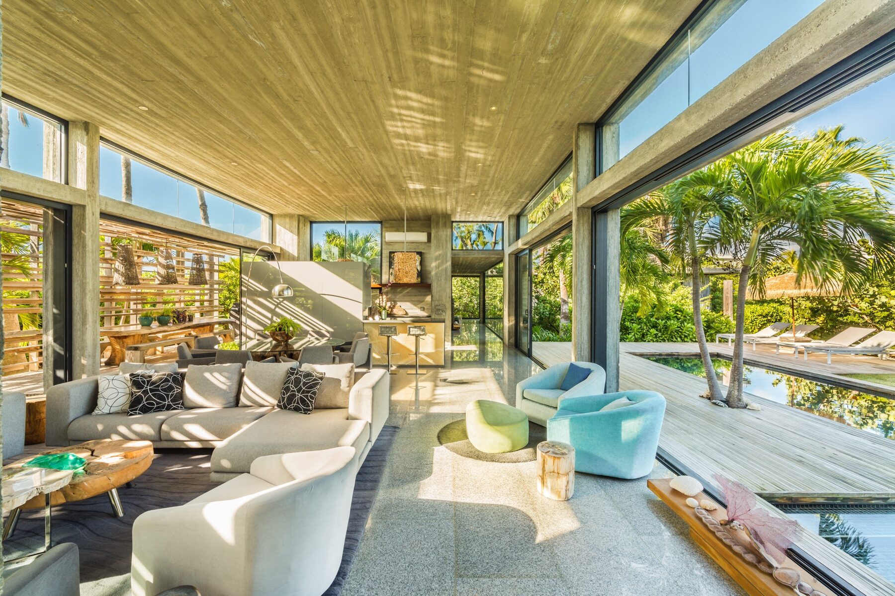 Concrete beam living room opening onto a palm shaded pool deck