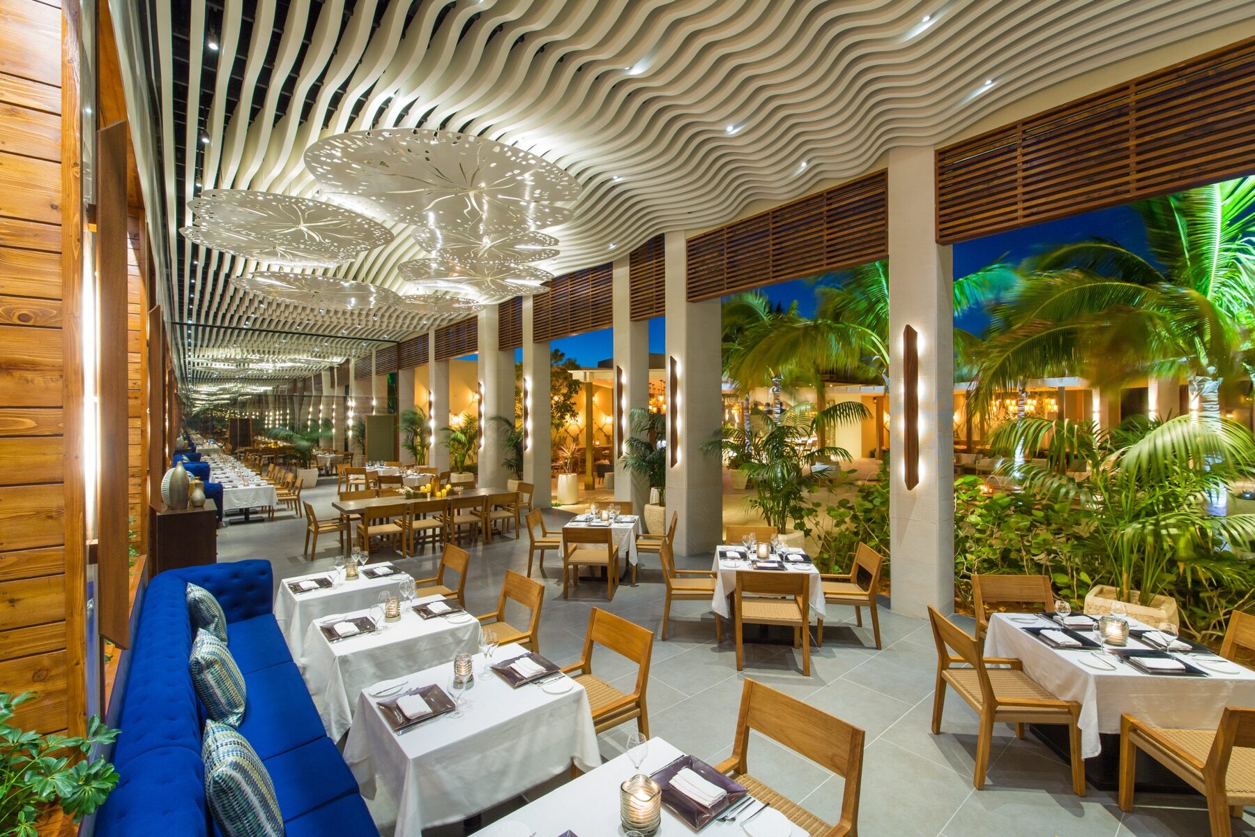 Open air resort restaurant with wavy ceiling lighting set for dinner