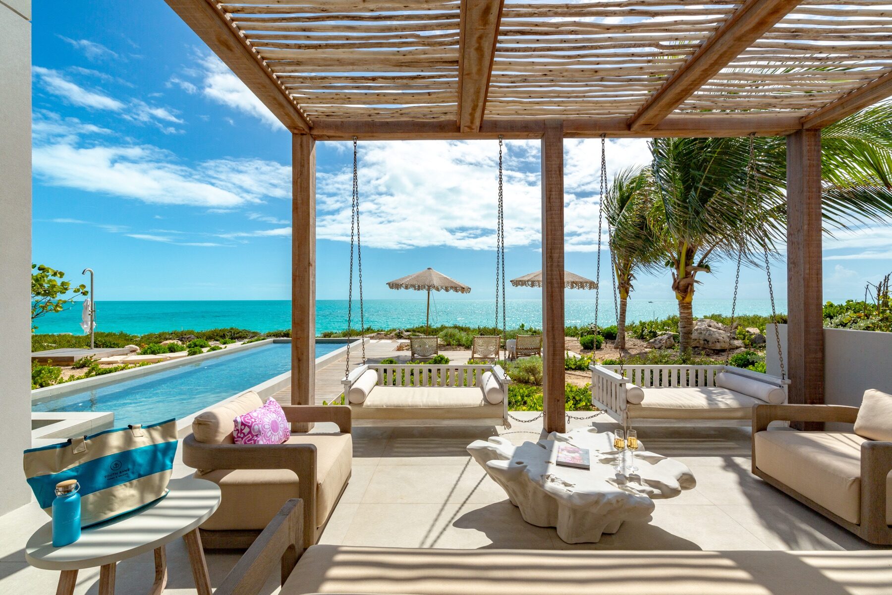 Shaded pergola swing seating overlooking a beachfront infinity pool
