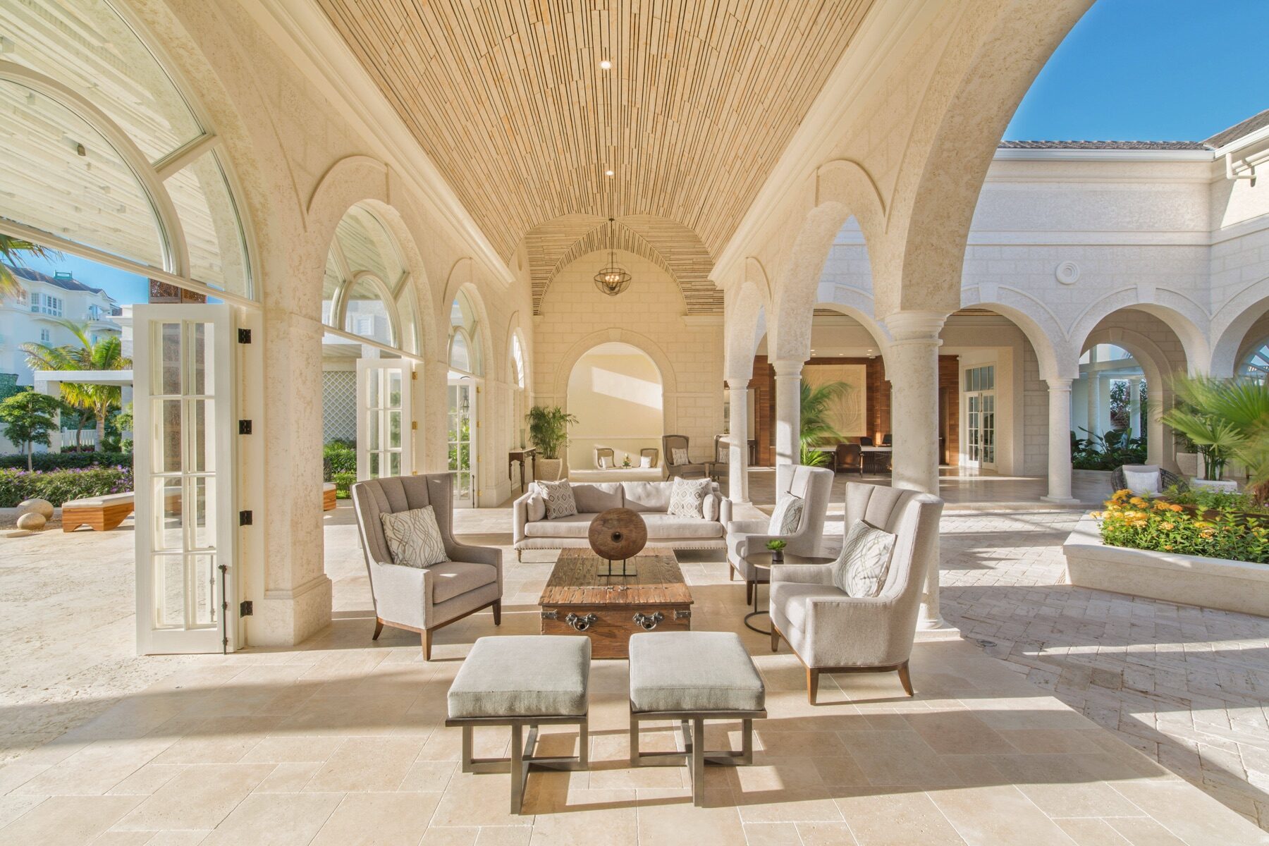 Arched stone loggia furnished with upholstered chairs and a wooden table