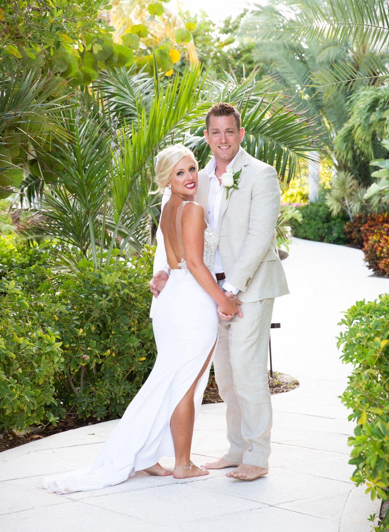 Bride and groom smiling together against lush green garden foliage