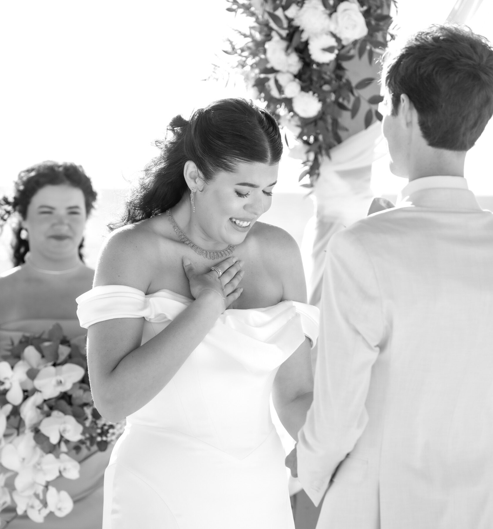 Emotional bride holding her hand to her chest during vows beside the groom