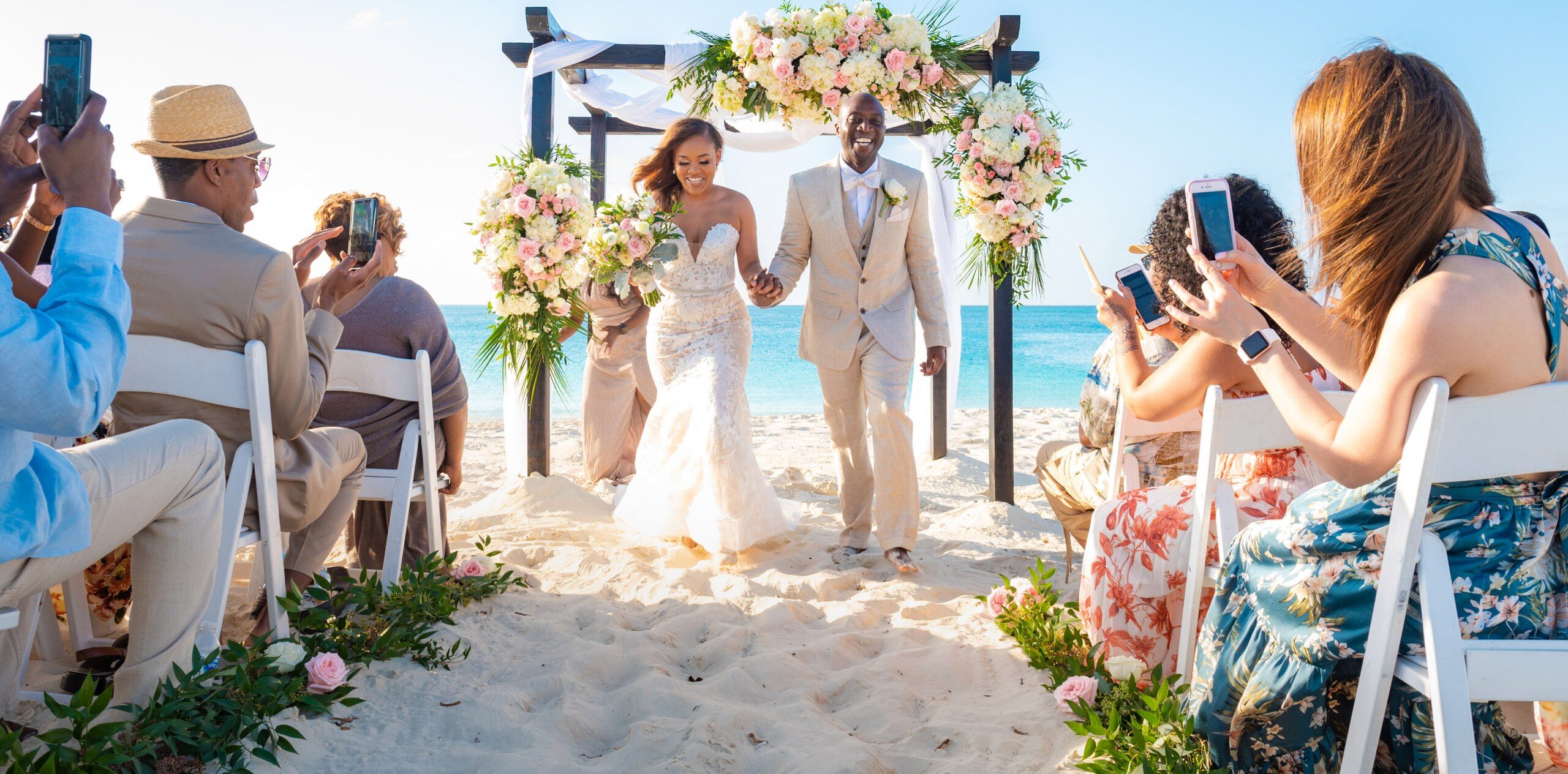 Bride and groom walking down the aisle as guests take photos